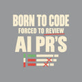 Cream uppercase type reads BORN TO CODE, FORCED TO REVIEW underlined in red, and AI PR'S in bold, above three diff-style bars in green, cream and red marked with red X's, on a mid-gray ground. Artwork shown on the Sport Grey garment colour.