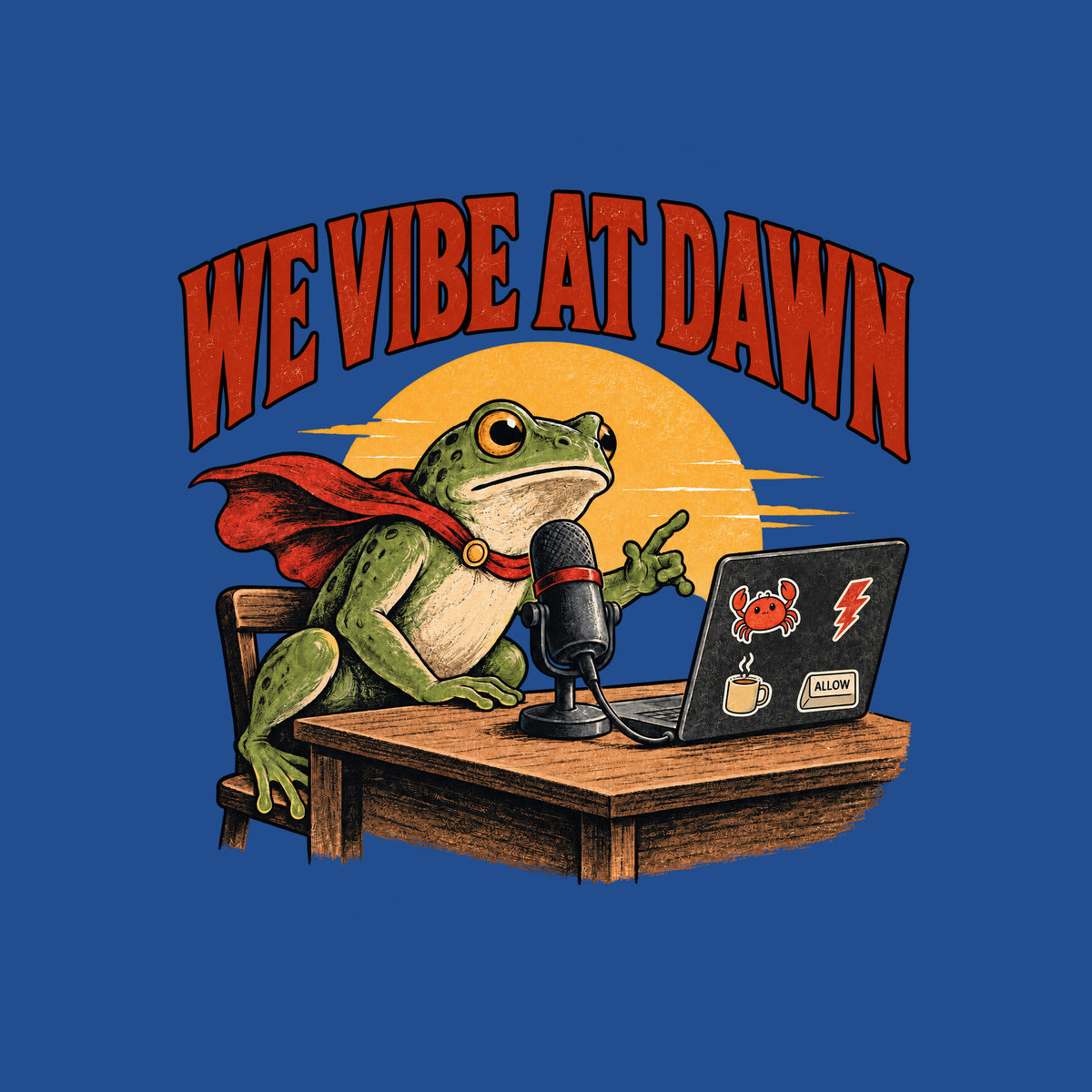 Illustrated frog wearing a red cape sits at a wooden desk before a microphone, one hand raised, beside a laptop with crab, lightning bolt, coffee mug and ALLOW stickers, under a yellow dawn sun and the arched red headline WE VIBE AT DAWN. Artwork shown on the Royal garment colour.